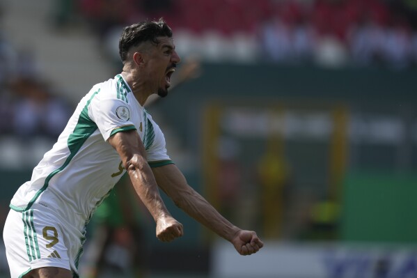 Algeria's Baghdad Bounedjah celebrates after scoring his side's opening goal during the African Cup of Nations Group D soccer match between Algeria and Burkina Faso at the Peace of Bouake stadium in Bouake, Ivory Coast, Saturday, Jan. 20, 2024. (AP Photo/Themba Hadebe)