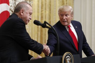 FILE - In this Nov. 13, 2019 file photo, President Donald Trump shakes hands with Turkish President Recep Tayyip Erdogan during a news conference in the East Room of the White House in Washington.  The State Department says recent congressional action to recognize the Armenian genocide does not reflect Trump administration policy. That statement is likely to pleaseErdogan. The Senate voted unanimously last week to recognize the mass killings of more than a million Armenians by Ottoman Turks a century ago as a genocide.  (AP Photo/Patrick Semansky)