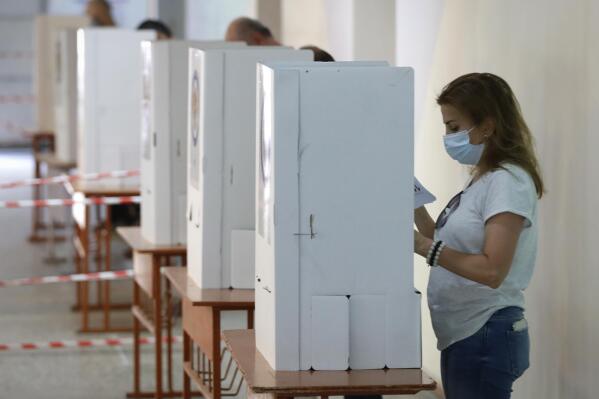 People read their ballot papers at a polling station during a parliamentary election in Yerevan, Armenia, Sunday, June 20, 2021. Armenians are voting in a national election after months of tensions over last year's defeat in fighting against Azerbaijan over the separatist region of Nagorno-Karabakh. (AP Photo/Sergei Grits)