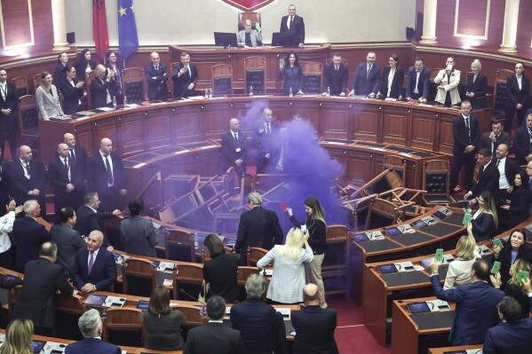 A coloured smoke bomb lit by Ervin Salianji an opposition lawmaker is seen during a parliament session in Tirana, Albania, Thursday, Nov. 2, 2023. Albanian opposition has tried to disrupt the parliamentary session in protest to what they called the authoritarian rule from the governing Socialist party. (AP Photo)