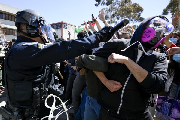 FILE - A protester is hit with a baton by a police officer at UC San Diego, May 6, 2024, in San Diego. As pro-Palestinian demonstrations escalate on college campuses around the country, critics of President Joe Biden’s handling of the Israel-Hamas war suggest this summer’s Democratic National Convention could be marred by protests and scenes of chaos that undermine his reelection. It raises the specter of a replay of 1968’s Democratic convention in Chicago, where a violent police crackdown created indelible scenes of chaos. (AP Photo/Denis Poroy, File)