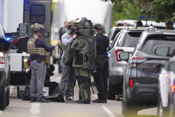 Law enforcement officials dress up in protective gear to investigative an attack on the Pearl Street Mall, Sunday, June 1, 2025, in Boulder, Colo. (AP Photo/David Zalubowski)