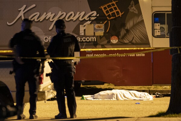 A victim covered with a cloth lies near a food truck after a car drove into a crowd at the Lapu Lapu Festival in Vancouver, British Columbia, Saturday April 26, 2025. (Rich Lam/The Canadian Press via AP)