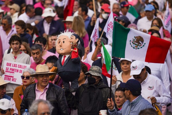 Demonstrators carry an effigy portraying Mexican President Andres Manuel Lopez Obrador and presidential candidate Claudia Sheinbaum during a march organized by citizen organizations demanding that electoral autonomy be respected in the upcoming general elections, in Mexico City, Sunday, Feb. 18, 2024. General elections in which voters will elect a new president and legislators are scheduled for June 2. (AP Photo/Marco Ugarte)