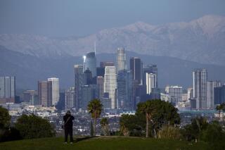 A visitor takes in a view of the city's skyline under the snow-covered San Gabriel mountains after a series of storms Thursday, March 2, 2023, in Los Angeles. (AP Photo/Marcio Jose Sanchez)