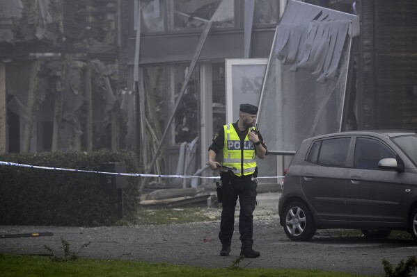 A police officer stands on the site of a powerful explosion that occurred early Thursday morning Sept. 28, 2023, in a housing area in Storvreta outside Uppsala, Sweden. A 25-year-old woman died in the blast. (Anders Wiklund/TT News Agency via AP)