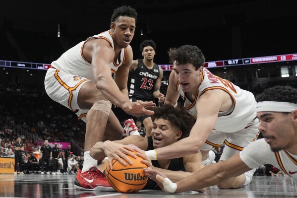 Cincinnati's Dan Skillings Jr. dives after a loose ball with Iowa State's Dishon Jackson, left, Milan Momcilovic, second from right, and Tamin Lipsey, right, as Cincinnati's Dillon Mitchell (23) watches during the first half of an NCAA college basketball game in the second round of the Big 12 Conference tournament, Wednesday, March 12, 2025, in Kansas City, Mo. (AP Photo/Charlie Riedel)