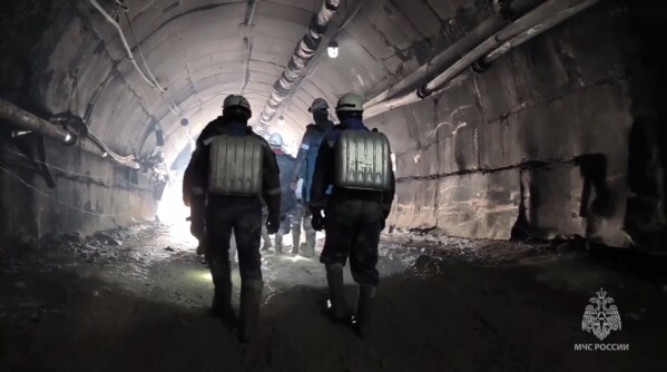 In this photo taken from video released by Russia Emergency Situations Ministry press service on Monday, March 25, 2024, Russia Emergency Situations employees walk inside the gold mine in Zeysk district, Amur region, eastern Russia. Rescue workers are laboring for eighth day to reach 13 people trapped deep underground in a collapsed gold mine in Russia's far east. (Russia Emergency Situations Ministry press service via AP)