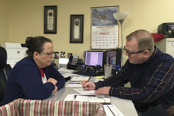 FILE - David Ermold, right, files to run for Rowan County Clerk in Kentucky as Clerk Kim Davis looks on, Dec. 6, 2017, in Morehead, Ky. Davis denied Ermold and his husband a marriage license in 2015 because she was opposed to gay marriage for religious reasons. Ermold and his partner won a jury verdict for damages against Davis on Wednesday, Sept. 13, 2023. (AP Photo/Adam Beam, File)