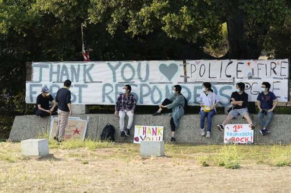 Students and researchers at UC Santa Cruz sit in front of a sign thanking first responders for their efforts in fighting the CZU August Lightning Complex Fire Monday, Aug. 24, 2020, in Santa Cruz, Calif. (AP Photo/Marcio Jose Sanchez)