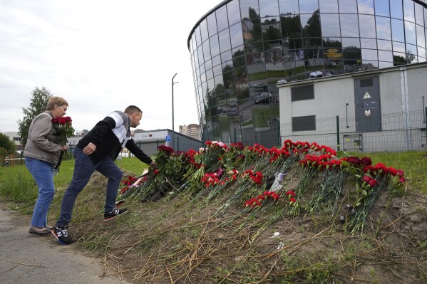 People lay flowers at an informal memorial next to the former 'PMC Wagner Centre' in St. Petersburg, Russia, Thursday, Aug. 24, 2023. Russian mercenary leader Yevgeny Prigozhin, the founder of the Wagner Group, reportedly died when a private jet he was said to be on crashed on Aug. 23, 2023, killing all 10 people on board. (AP Photo/Dmitri Lovetsky)