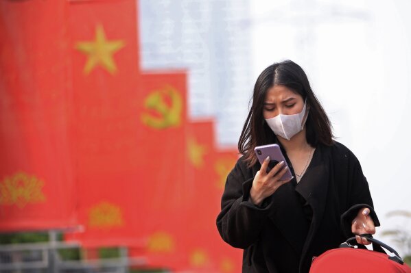 In this Jan. 23, 2021, file photo, a woman wearing face mask looks at her phone in Hanoi, Vietnam. Amnesty International has found that a hacking group known as Ocean Lotus has been staging more sp...
