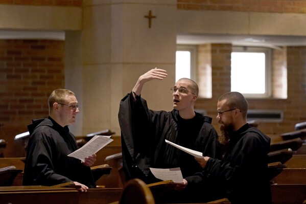 Los hermanos Leven Barton, izquierda, Florian Rumpza, centro, y Angelus Atkinson, cantan en latín durante la misa católica en el Benedictine College el domingo 3 de diciembre de 2023, en Atchison, Kansas (Foto AP/Charlie Riedel).