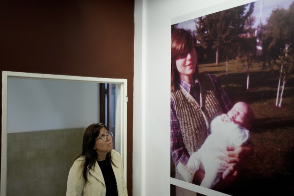 Claudia Poblete poses for a photo next to an image of herself as an infant and her disappeared mother Marta Gertrudis, at the Museum of Space for Memory and the Promotion and Defense of Human Rights, in Buenos Aires, Argentina, Friday, March 22, 2024. Back in the year 2000, Poblete didn’t go by her current name. She was called Mercedes Landa, and before a judge showed her a DNA test result that confirmed her true identity, she was unaware that she was among hundreds of babies who were abducted during the country's military dictatorship. (AP Photo/Natacha Pisarenko)