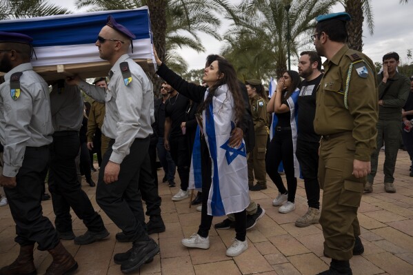 The wife of Israeli reservist Yair Cohen touches his flag-draped casket during his funeral at Kiryat Shaul military cemetery in Tel Aviv, Israel, Tuesday, Feb. 13, 2024. Cohen, 30, was killed during Israel's ground operation in the Gaza Strip, where the Israeli army has been battling Palestinian militants in the war ignited by Hamas' Oct. 7 attack into Israel. (AP Photo/Oded Balilty)