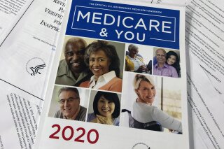 The Official U.S. Government Medicare Handbook for 2020 over pages of a Department of Health and Human Services, Office of the Inspector General report, are shown, Thursday, Feb. 13, 2020 in Washington. A government watchdog tells The Associated Press it will launch a nationwide audit that may shed light on how seniors’ personal Medicare information is getting to telemarketers, raising concerns about fraud and waste. An official with the Health and Human Services inspector general's office says the audit will be announced next week. (AP Photos/Wayne Partlow)