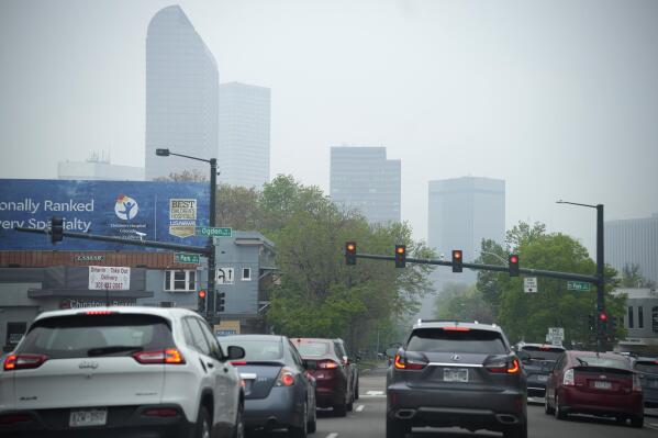Motorists wait for a red light on westbound 18th Avenue at Park Avenue as smoke shrouds the skyline Friday, May 19, 2023, in downtown Denver. Smoke from numerous fires in the Canadian province of Alberta has rolled into Colorado Friday, giving Denver a ranking of third worst air quality of all major cities globally. The Colorado Department of Public Health and Education has issued an air quality health advisory alert as a result of the inflow of smoke across the Centennial State. (AP Photo/David Zalubowski)