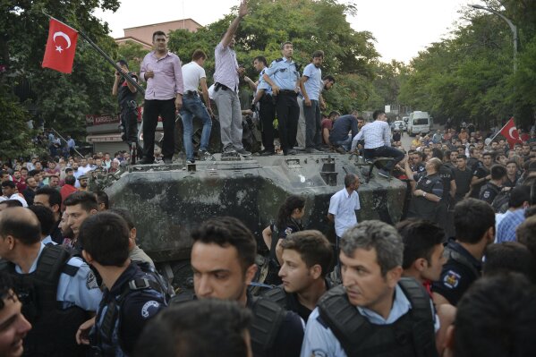 
              FILE - In this Saturday, July 16, 2016 file photo, people gather and some stand atop of a Turkish army armoured vehicle in Ankara, Turkey, during the attempted coup. A year ago Saturday a group of Turkish soldiers using tanks, warplanes and helicopters launched a plot to overthrow Turkey’s president and government. The coup attempt failed, but the fallout continues a year later. (AP Photo, File)
            