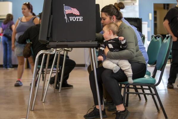 Miranda Padilla holds her 11-month-old son Grayson Sanchez while marking her ballot at a polling center in the South Valley area of Albuquerque, N.M., Tuesday, Nov. 8, 2022 (AP Photo/Andres Leighton)