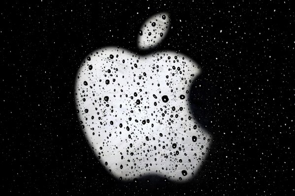FILE - In this Dec. 26, 2018, file photo, an Apple logo is seen in raindrops on a window outside an Apple Store at the Country Club Plaza shopping district in Kansas City, Mo.  Apple and Google launched a major joint effort, Friday, April 10, 2020,  to leverage smartphone technology contain the COVID-19 pandemic. New software the companies plan to add to phones would make it easier to use Bluetooth wireless technology to track down people who may have been infected by coronavirus carriers. (AP Photo/Charlie Riedel, File)