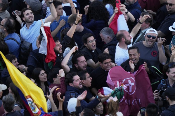 People react as white smoke billows from the chimney of the Sistine Chapel where 133 cardinals are gathering on the second day of the conclave to elect a successor to late Pope Francis, at the Vatican, Thursday, May 8, 2025. (AP Photo/Luca Bruno)