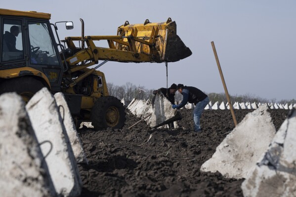 2024年4月17日水曜日、ウクライナ・ハリコフ地方のロシア国境近くで新たな防御陣地を建設する際に、「ドラゴンの歯」として知られる対戦車防御装置を設置する作業員たち。(AP写真/エフゲニー・マロレトカ)