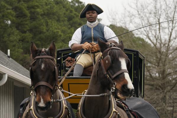 Colonial Williamsburg coachman Collin Ashe directs his horses as he drives his coach Thursday Feb. 24, 2022, in Williamsburg, Va. Colonial Williamsburg has begun to honor the coachmen by naming a new carriage after one of them. (AP Photo/Steve Helber)