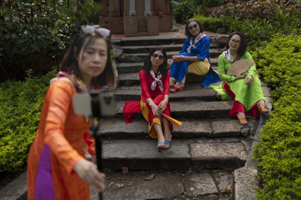 Anh Nguyen, foreground, sets up her phone to take a group photo with her friends at a park in Ho Chi Minh City, Vietnam, Jan. 14, 2024. (AP Photo/Jae C. Hong)
