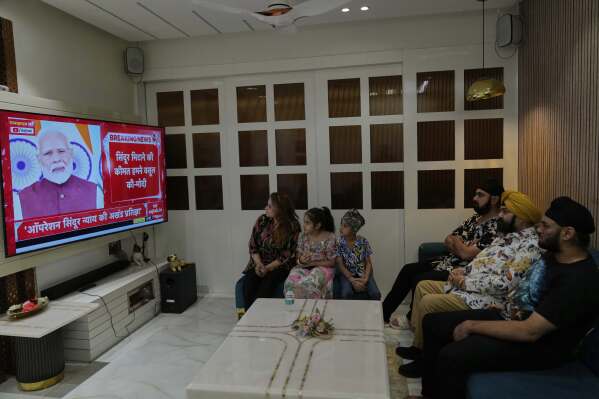 Family members watch the live telecast of Indian Prime Minister Narendra Modi's speech on a television at their residence in Hyderabad, India, Monday, May 12, 2025. (AP Photo/Mahesh Kumar A.)