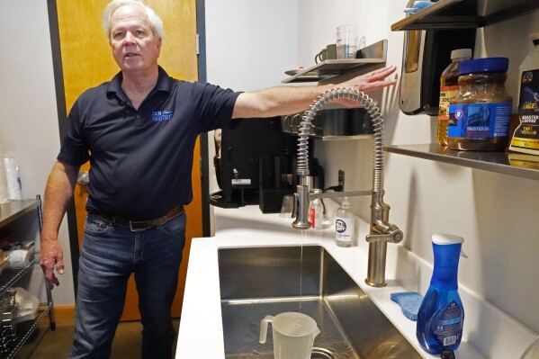 FILE - Ted Henifin, interim water manager for JXN Water, the water system for the city of Jackson, Miss., demonstrates how to run faucet water like a "thin line of spaghetti with intermittent breaks" in order to deal with expected below freezing weather, at a news conference in Jackson, Miss., Friday, Jan. 12, 2024. Law enforcement agencies are investigating whether social media rumors about a potential water outage prompted people to quickly fill containers with tap water in Mississippi's capital during a cold snap and cause a drop in pressure that temporarily made taps run dry to thousands of households on the city’s long-troubled system. (AP Photo/Rogelio V. Solis, File)