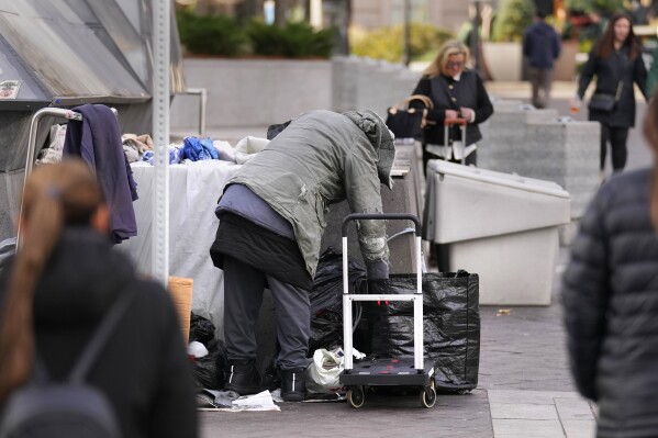 FILE - A homeless man repacks his belongings on a sidewalk outside South Station, Nov. 15, 2023, in Boston. Massachusetts Gov. Maura Healey is turning to a former prison, the Bay State Correctional Center, as a temporary safety-net shelter for families experiencing homelessness. (AP Photo/Charles Krupa, File)