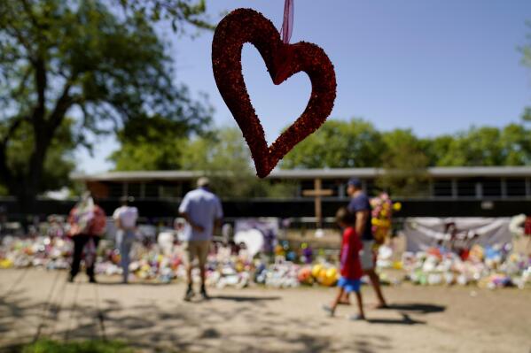 Mourners visit a make-shift memorial honoring the school shooting victims at Robb Elementary, Monday, July 11, 2022, in Uvalde, Texas.   Students who survived the May 24 shooting at an elementary school in Uvalde, Texas are spending the summer grappling with post-traumatic stress disorder. Meanwhile, parents find themselves unable to help them, worried the tragedy at Robb Elementary struck a largely Hispanic town as Latinos continue to face disparities to access mental health care.  (AP Photo/Eric Gay)