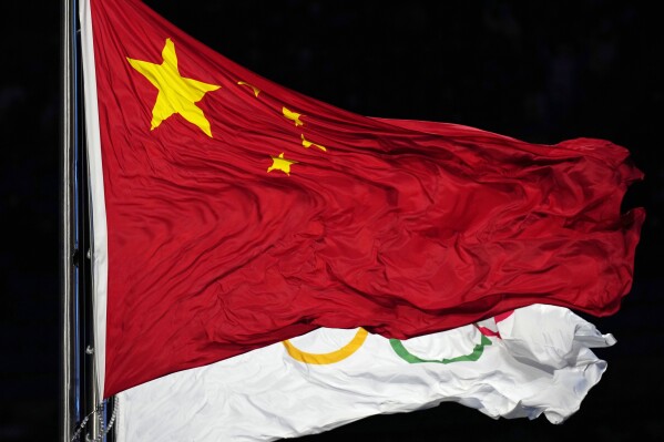 FILE - The Chinese and the Olympic flag wave during the opening ceremony of the 2022 Winter Olympics, Feb. 4, 2022, in Beijing. In the two years before the World Anti-Doping Agency cleared 23 Chinese swimmers of doping allegations, that country’s government contributed nearly $2 million in additional funding to WADA programs, including one designed to strengthen the agency’s investigations and intelligence unit. (AP Photo/Petr David Josek, file)