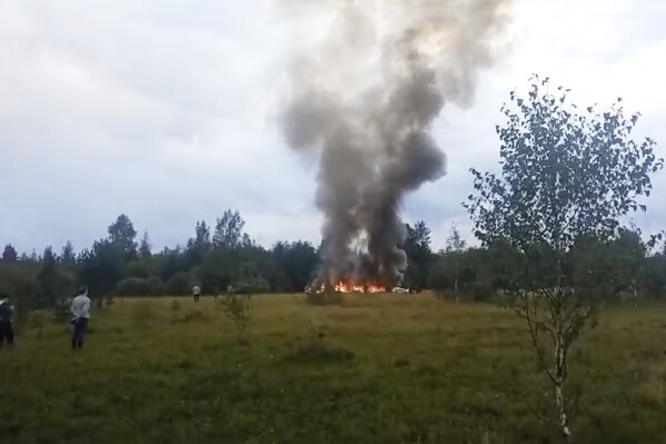 In this image taken from video, smoke and flames rise from a crashed private jet near the village of Kuzhenkino, Tver region, Russia, Wednesday, Aug. 23, 2023. Russian mercenary leader Yevgeny V. Prigozhin, the founder of the Wagner Group, reportedly died when a private jet he was said to be on crashed on Aug. 23, 2023, killing all 10 people on board. (AP Photo)