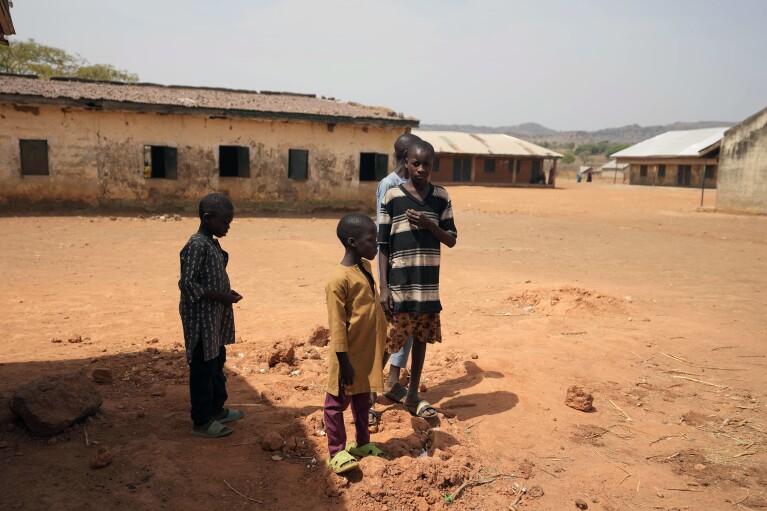 Children stand outside the LEA Primary and Secondary School Kuriga where students were kidnapped in Kuriga, Kaduna state, Nigeria, Saturday, March 9, 2024. Security forces swept through large forests in Nigeria's northwest region on Friday in search of nearly 300 children who were abducted from their school a day earlier in the West African nation's latest mass kidnap which analysts and activists blamed on the failure of intelligence and slow security response. (AP Photo/Sunday Alamba)