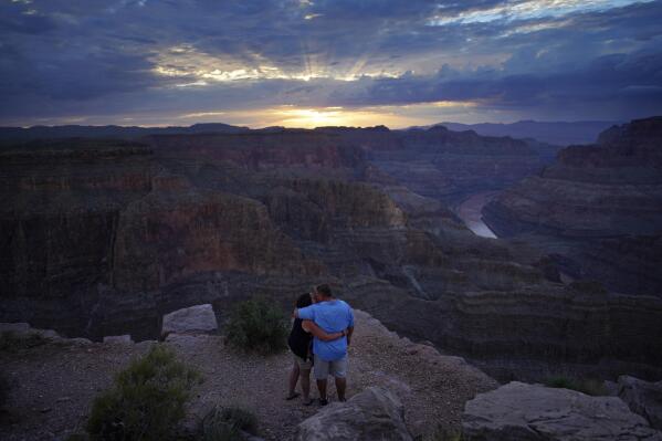 Alyssa Chubbuck, left, and Dan Bennett embrace while watching the sunset at Guano Point overlooking the Colorado River on the Hualapai reservation Monday, Aug. 15, 2022, in northwestern Arizona. Roughly 600,000 tourists a year visit the Grand Canyon on the Hualapai reservation in northwestern Arizona — an operation that's the tribe's main source of revenue. (AP Photo/John Locher)