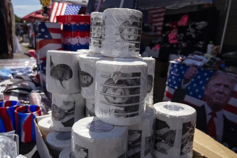 Merchandise, including toilet paper with the image of former Secretary of State Hillary Clinton, is displayed during the ReAwaken America Tour at Cornerstone Church in Batavia, N.Y., Saturday, Aug. 13, 2022. Du Mez, who is writing a book on the overlap of consumerism and Christian identity, says events like this are orchestrated to extract money from participants. They are invited to participate in the movement by pulling out their credit cards. “People give it happily. The skeptical take is this is a scam. That’s not how it feels to the people who are giving their money,” she says. (AP Photo/Carolyn Kaster)