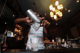 FILE - In this Thursday, July 9, 2020 file photo, a bartender makes a cocktail in New Orleans. A report released Wednesday, July 15, 2020, finds if you decide to have an alcoholic drink, limiting yourself to one a day is best — whether you’re a man or woman. (AP Photo/Gerald Herbert)