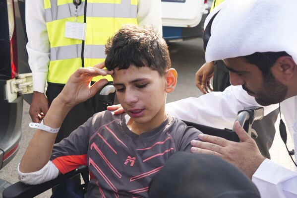 Twelve-year-old Amr Jandieh, who was wounded in the Israel-Hamas war, gestures, while surrounded by Emirati officials as he is brought down from the plane to an ambulance in Abu Dhabi, United Arab Emirates, Saturday, Nov. 18, 2023. Jandieh is one of thousands of children in Gaza who have been injured by the ongoing Hamas-Israel war. But he’s one of the slightly luckier ones who was able to leave the besieged enclave to get treatment outside. (AP Photo/Malak Harb)