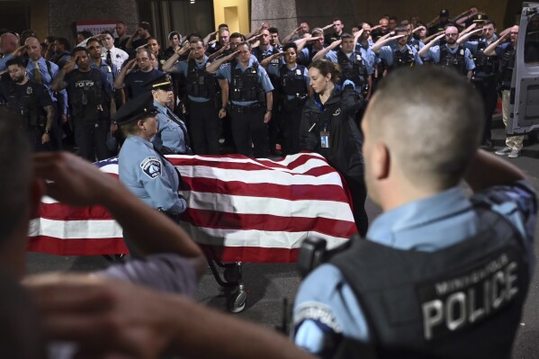 Law enforcement officers salute the flag-draped remains of fallen Minneapolis police Officer Jamal Mitchell as he is escorted to a waiting medical examiner's vehicle outside Hennepin County Medical Center in Minneapolis, Thursday, May 30, 2024. Mitchell was killed earlier in the day while responding to a shooting call. (Aaron Lavinsky/Star Tribune via AP)