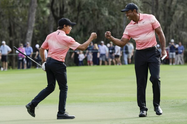 FILE - Tiger Woods, right, fist bumps his son Charlie Woods, left, after finishing the ninth hole during the first round of the PNC Championship golf tournament Saturday, Dec. 17, 2022, in Orlando, Fla. Tiger Woods is feeling good enough that he turned down a cart and chose to walk 18 holes in the PNC Championship pro-am. His 14-year-old son, Charlie, is hitting it long enough that he had to move back a tee. (AP Photo/Kevin Kolczynski, File)