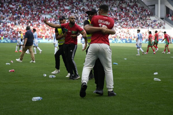 Stewards catch pitch invaders during the men's Group B soccer match between Argentina and Morocco at Geoffroy-Guichard Stadium at the 2024 Summer Olympics, Wednesday, July 24, 2024, in Saint-Etienne, France. (ĢӰԺ Photo/Silvia Izquierdo)
