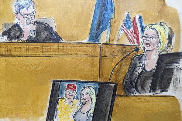 En este dibujo del tribunal, Stormy Daniels testifica en el estrado mientras el juez Juan Merchan observa, el martes 7 de mayo de 2024, en Nueva York. En una pantalla, se muestra una fotografía de Donald Trump y Daniels de su primer encuentro. (Elizabeth Williams vía AP)