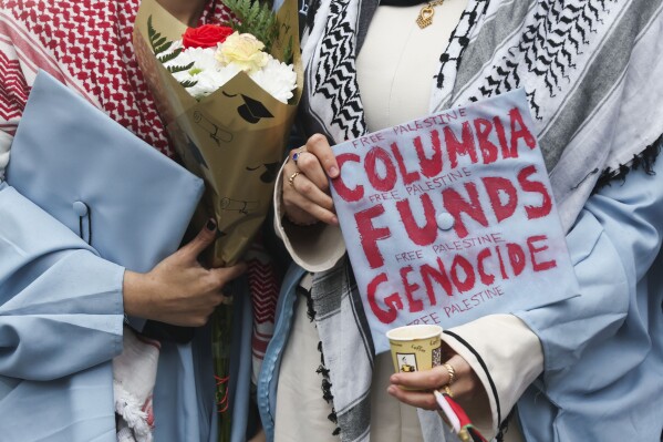 Alumni will show off their decorated caps in support of Palestinians on Wednesday, May 21, 2025, in New York, taking photos across the street from the main gate of Columbia University. (AP Photo/Heather Khalifa)