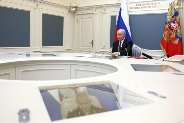 Russian President Vladimir Putin conducts training with the forces and means of the ground, sea and air components of the nuclear deterrent forces in Moscow, Russia, Wednesday, Oct. 25, 2023. During the training, practical launches of ballistic and cruise missiles took place, the Kremlin said in a statement. Russian Defense Minister Sergei Shoigu is seen on the screen bottom. (Gavriil Grigorov, Sputnik, Kremlin Pool Photo via AP)