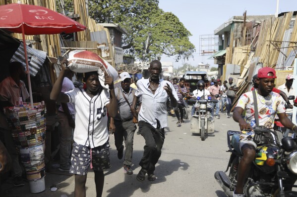 Pedestrians run for cover after hearing gunshots in Port-au-Prince, Haiti, Thursday, March 7, 2024. (AP Photo/Odelyn Joseph)