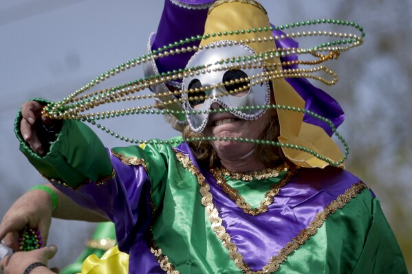 FILE - A rider tosses beads as the Krewe of Argus rolls to the theme 'Argus is Golden,' during its 50th anniversary Tuesday, Feb. 21, 2023, in Metairie, La. It’s a beloved Carnival season tradition in New Orleans — masked riders on lavish floats fling string of beads or other trinkets to parade watchers. But the huge amount of non-biodegradable plastic beads that wind up amid all the other Mardi Gras trash worries environmentalists. (Scott Threlkeld/The Times-Picayune/The New Orleans Advocate via AP, File)