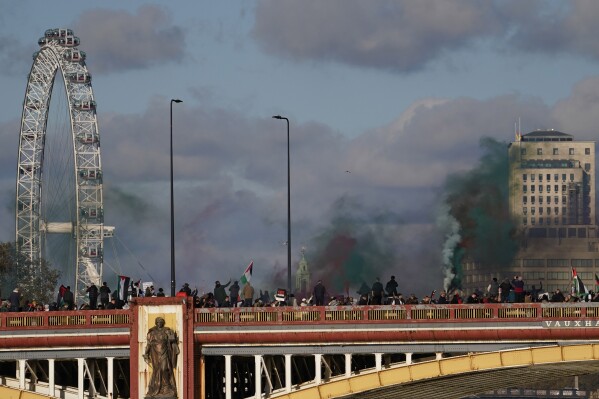 Protesters wave flags and hold flares during a pro-Palestinian protest in London, Saturday, Nov. 11, 2023. London police have stepped up efforts to ensure a pro-Palestinian march on Saturday remains peaceful following a week of political sparring over whether the demonstration should go ahead on the weekend Britain honors its war dead.(AP Photo/Alberto Pezzali)