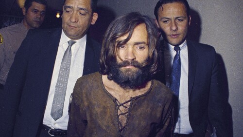 Archivo - Charles Manson es escoltado a un tribunal para escuchar la lectura de cargos por cargos de asociación ilícita y asesinato en relación con el homicidio de Sharon Tate en Los Ángeles en 1969. (AP Foto/Archivo)