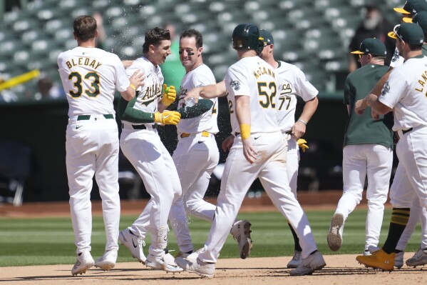 Oakland Athletics' Tyler Soderstrom, second from left, celebrates with JJ Bleday (33) and teammates after walking with the bases loaded to score the winning run during the 11th inning of a baseball game against the Colorado Rockies in Oakland, Calif., Thursday, May 23, 2024. (AP Photo/Jeff Chiu)